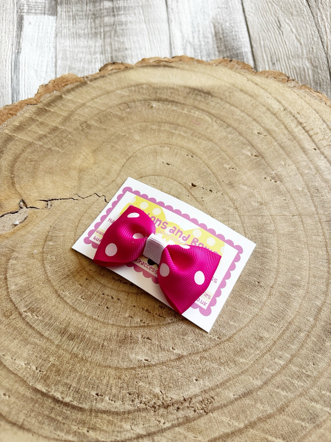 Bright pink polka dot handmade hair bow on Buttons and Bows display card