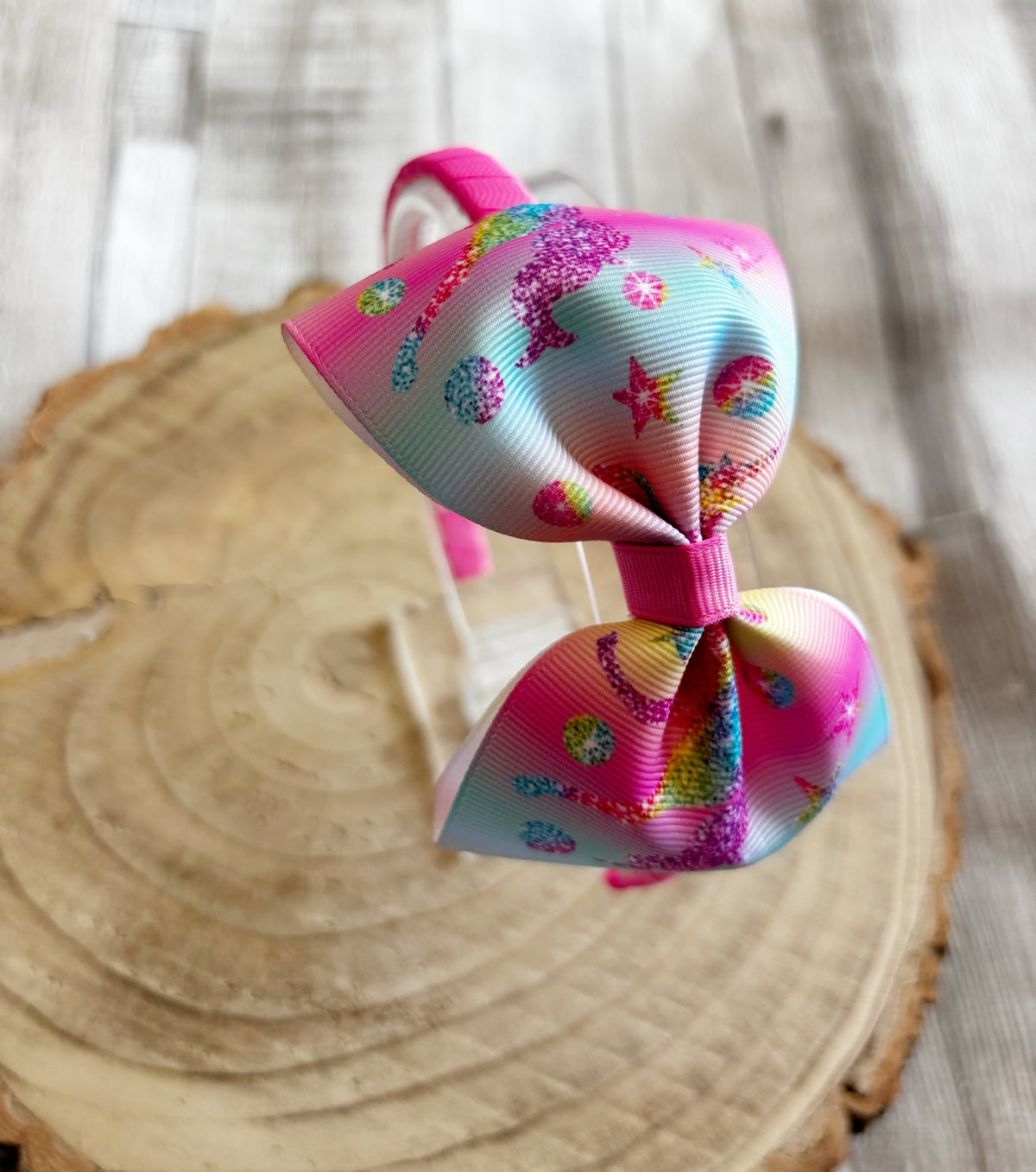 Close-up of rainbow dinosaur print bow headband handmade by Buttons and Bows